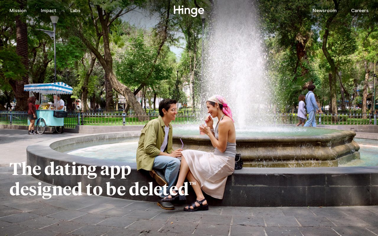 Hinge homepage showing a couple sitting on the edge of a park fountain with the tagline The dating app designed to be deleted